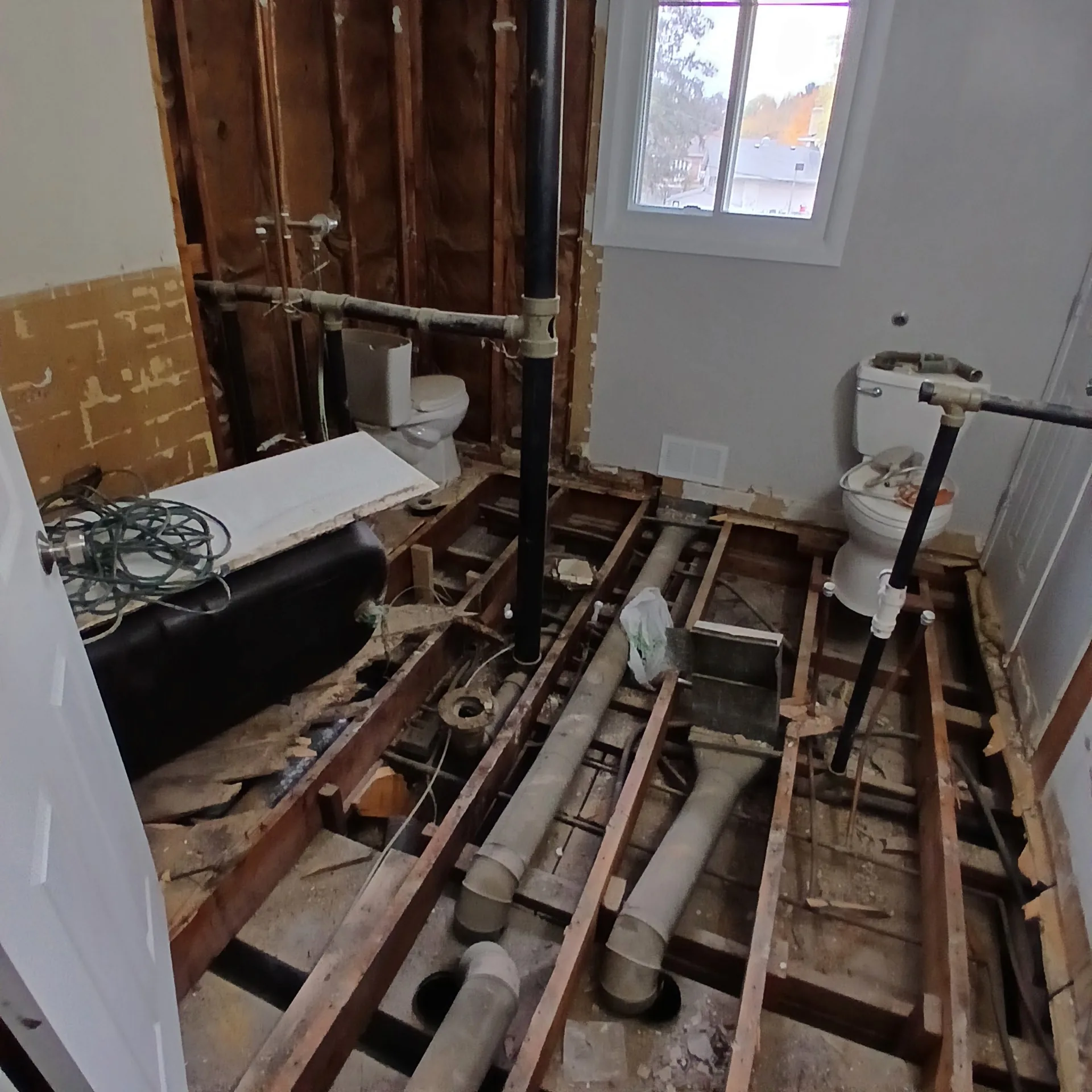Bathroom demolition showing subfloor and plumbing